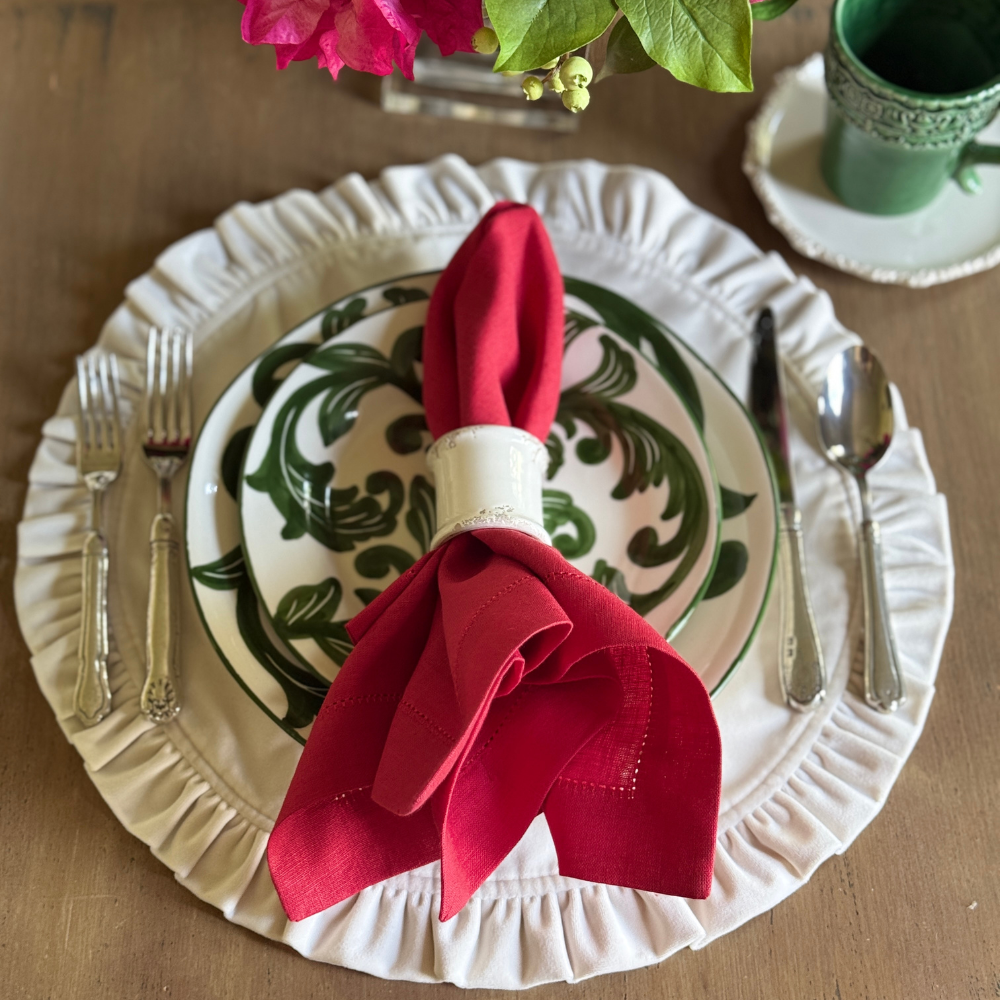Dining table setting with a red napkin, Al Fresco plate, and silverware on a wooden surface.
