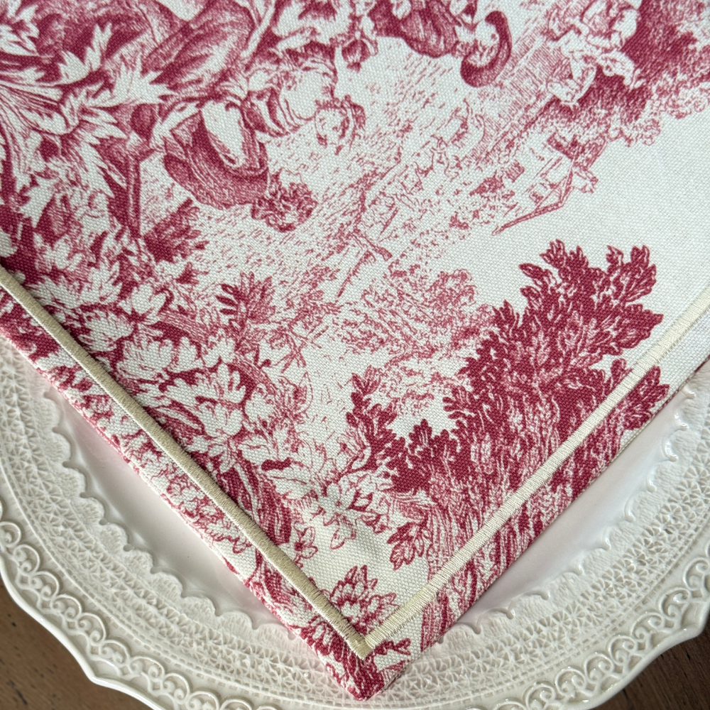 Montefalco Toile Cotton Napkin in Red and Cream on a Plate showing close up of corner