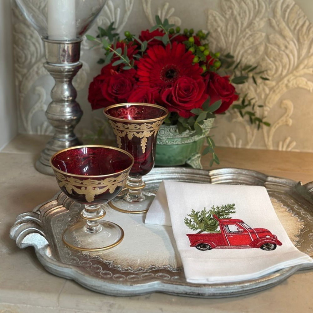 Vetro Red Gold goblets, silver candlestick, and Linen Towel with truck design with tree in back on Florentino tray.