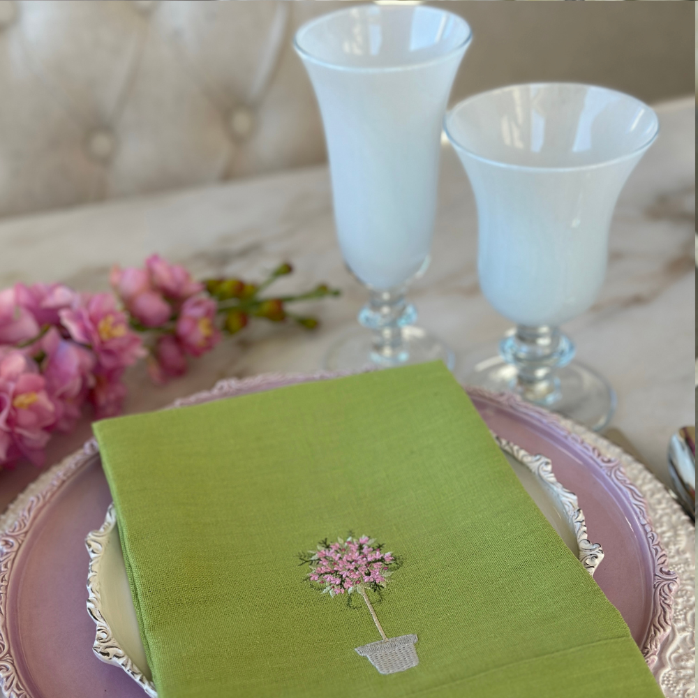 Rialto Italian Water Wine Glass and Flute in White on a table with flowers and a Pink Topiary embroidered linen napkin