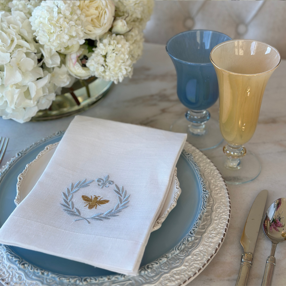 Rialto Blue Italian Water Wine Glass and Yellow Flute next to a place setting with an Italian Bee Tri-Fold linen Napkin