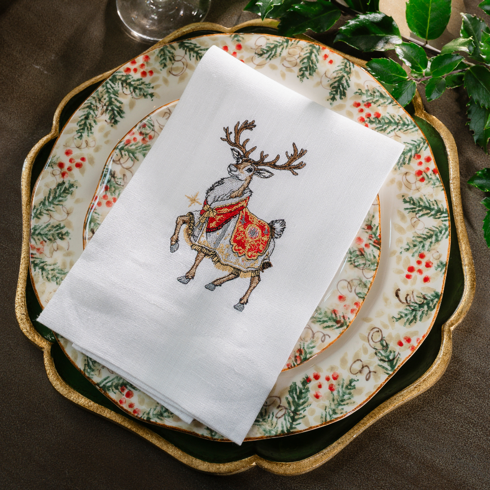 Royal Reindeer White Linen Towel folded on a Natale plate with greenery
