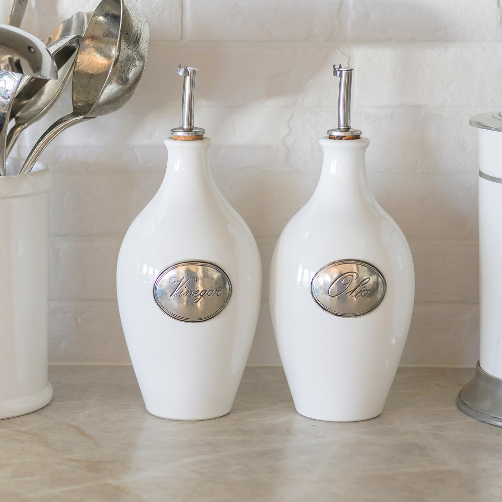 A Tuscan ceramic Vinegar bottle and Oil Bottle on a counter with white tile background