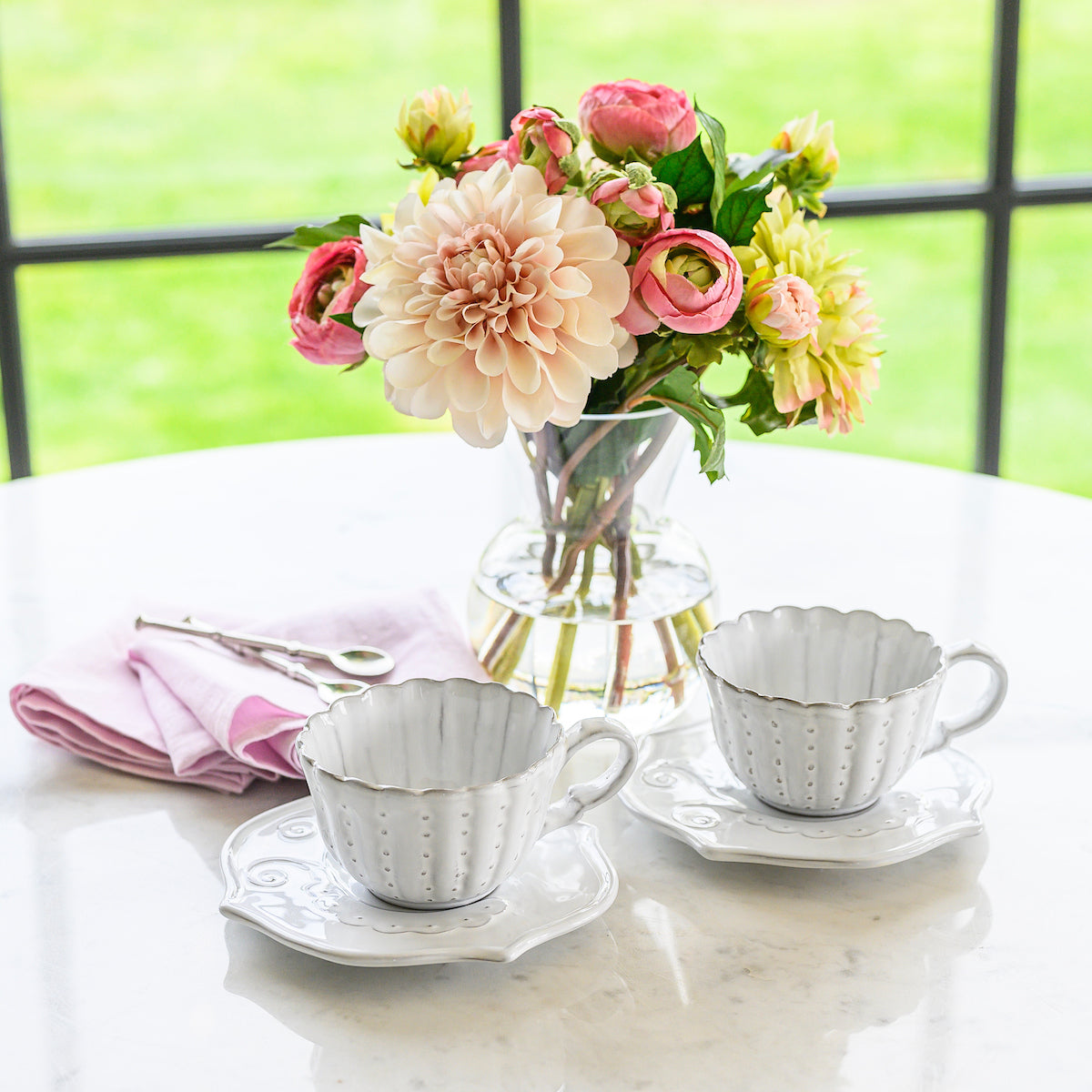 arte-italica-bella-bianca-tea-cup-stoneware set of 2 with saucers on marble table with flowers.