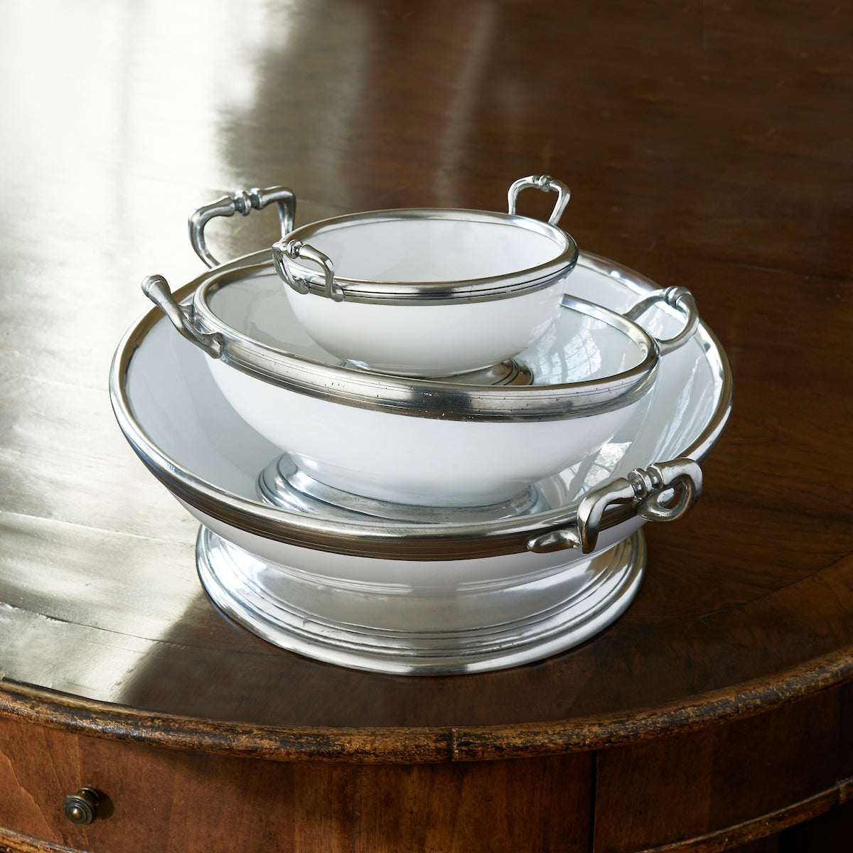 Large Tuscan footed bowl with handles in bianco white ceramic and pewter accents, ideal for serving pasta or salads. Shown stacked with other bowl product