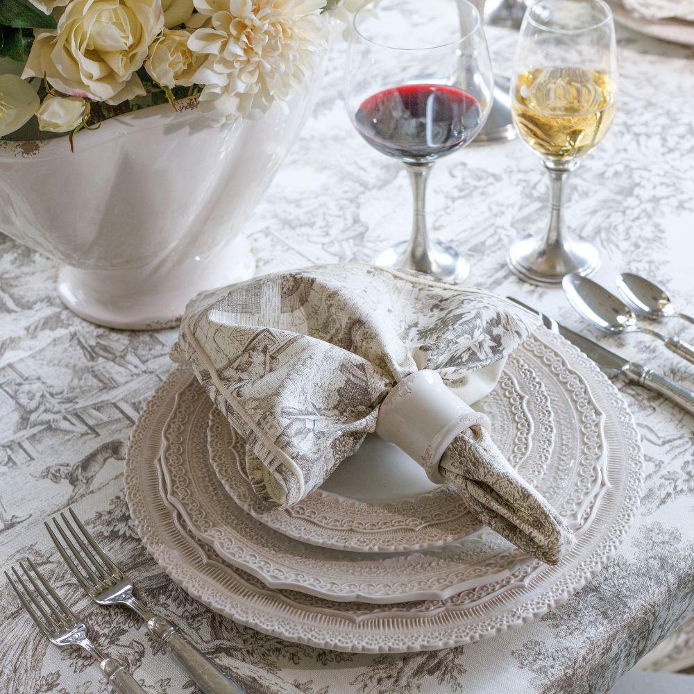 Montefalco Toile Latte and Cream Cotton Napkin on a table scape sitting on a stack of Cream Finezza Diner Plates by Arte Italica