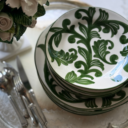 Stack of Al Fresco plates with silverware and flowers on a table.
