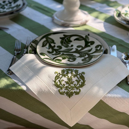 Detailed shot of hand-painted green design on Al Fresco plates, styled on table with green and white linens. 