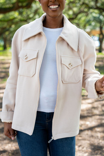 Woman wearing a latte colored wool blend Alex jacket with a blurred natural background