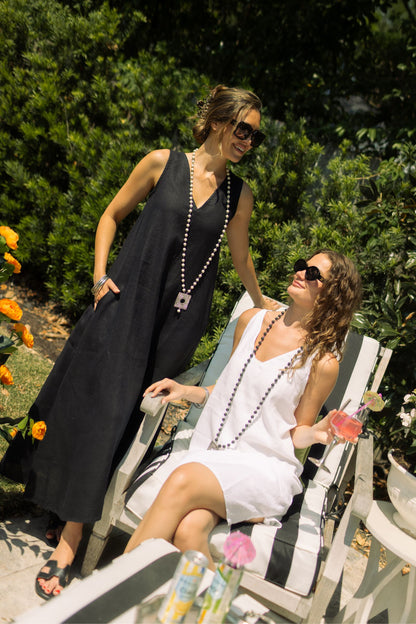 Two women posing outdoors, one wearing black linen Katherine dress paired with Boho necklace. --Arte Italica and Crown Linen Designs