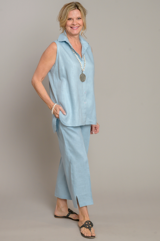 Woman wearing light blue sleeveless linen Caroline top with light blue linen Classic capri pants paired with a beaded necklace. --Arte Italica and Crown Linen Designs