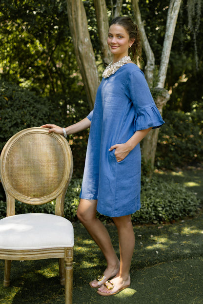 Woman standing outdoors in blue linen Bethany dress paired with pearl beaded cluster necklace and pewter bangles. --Arte Italica and Crown Linen Designs
