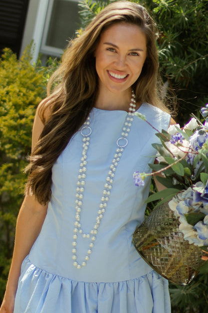 Woman posing in light blue taffeta dress wearing silver double pearl strand necklace. --Arte Italica and Crown Linen Designs