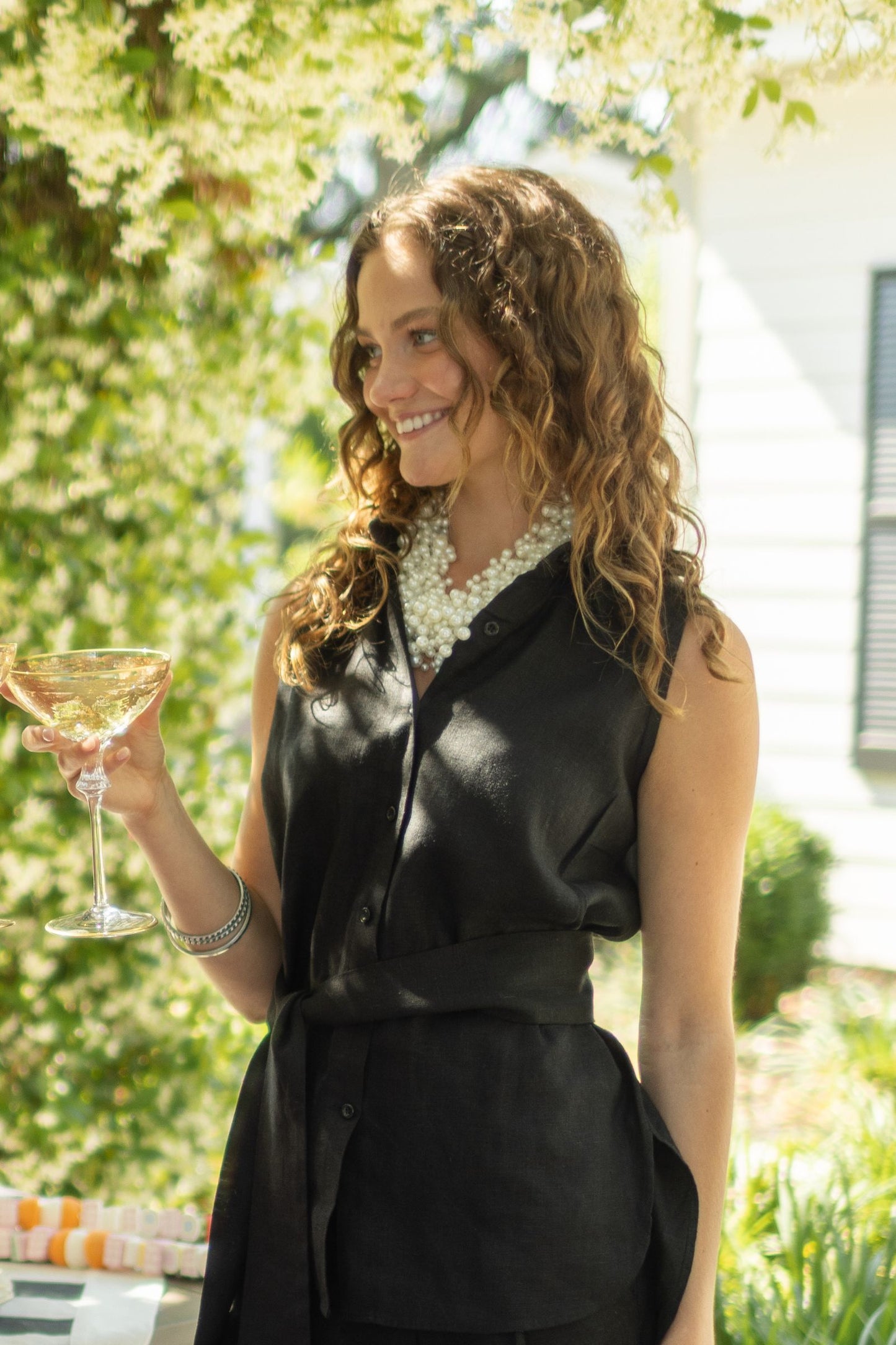 Woman wearing black linen outfit paired with ivory Pearl and Bead Cluster Necklace. --Arte Italica and Crown Linen Designs