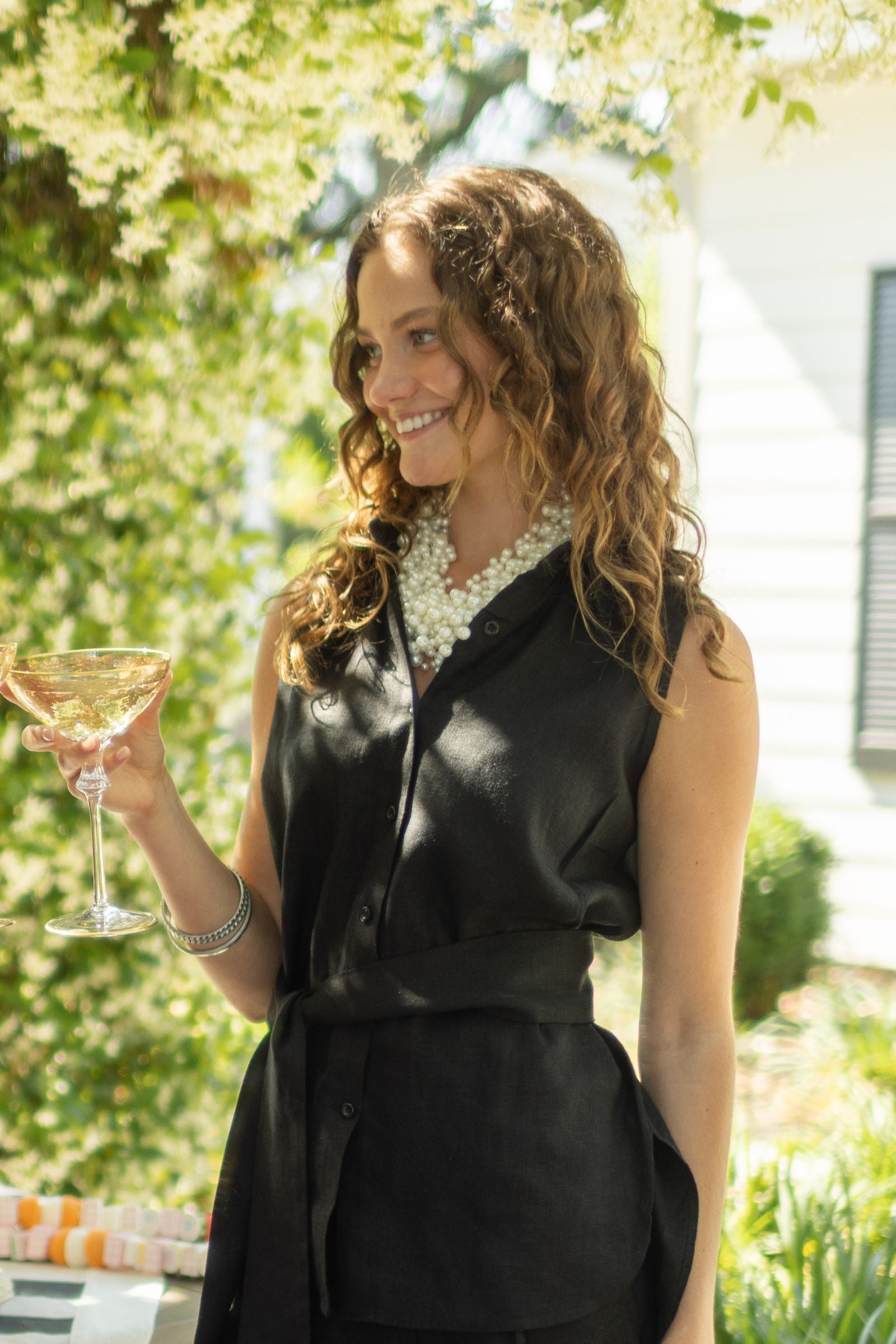 Woman wearing black linen outfit paired with ivory Pearl and Bead Cluster Necklace. --Arte Italica and Crown Linen Designs