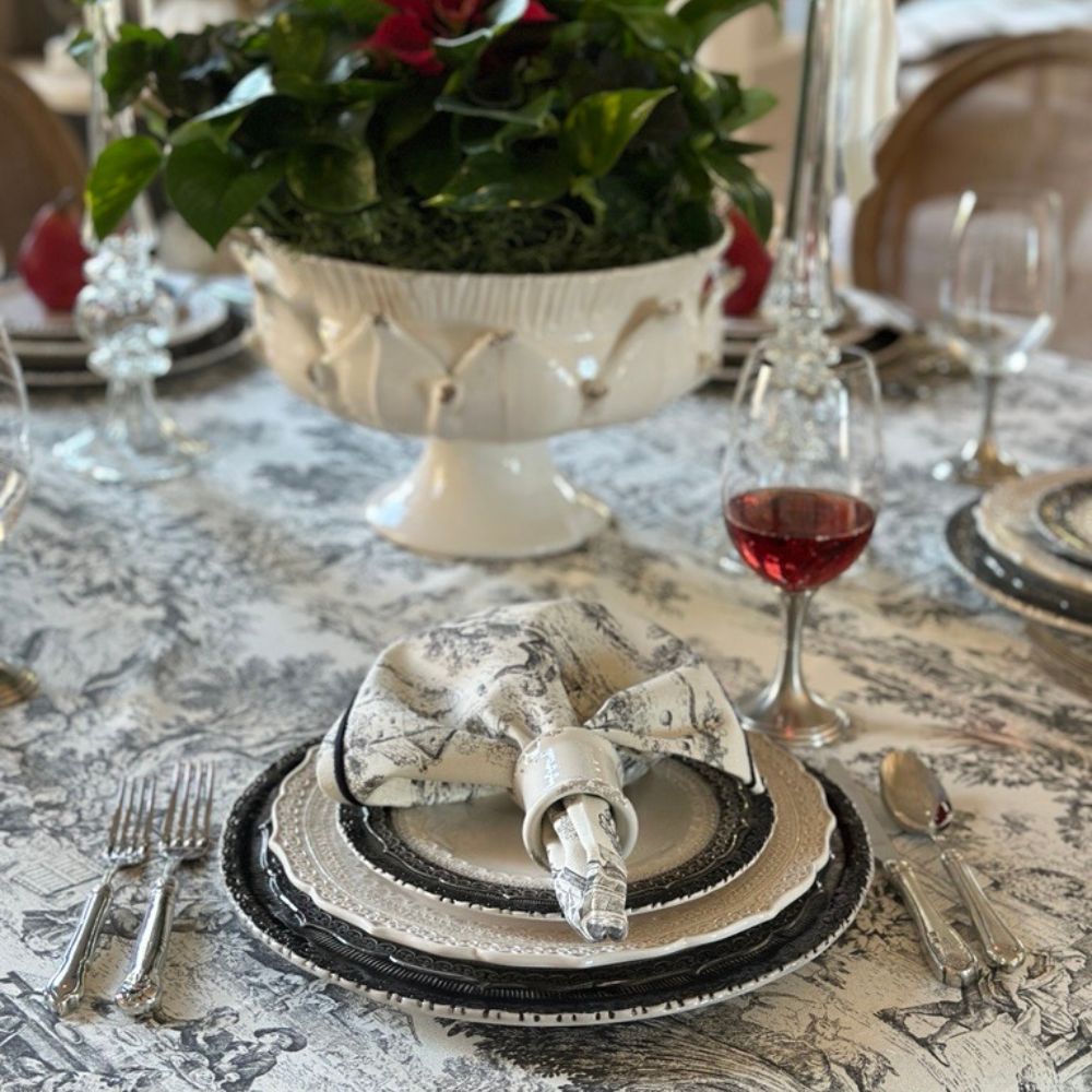 Elegant table setting with Finezza plates, Maltefalco black and cream toile napkins, and cutlery on a decorative toile tablecloth.