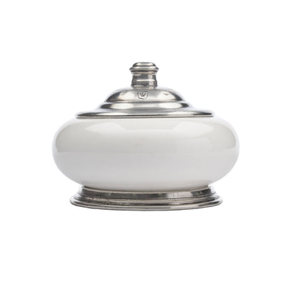 A round Tuscan keepsake box with a white ceramic body and pewter lid, featuring a decorative pattern typical of the Tuscan style.