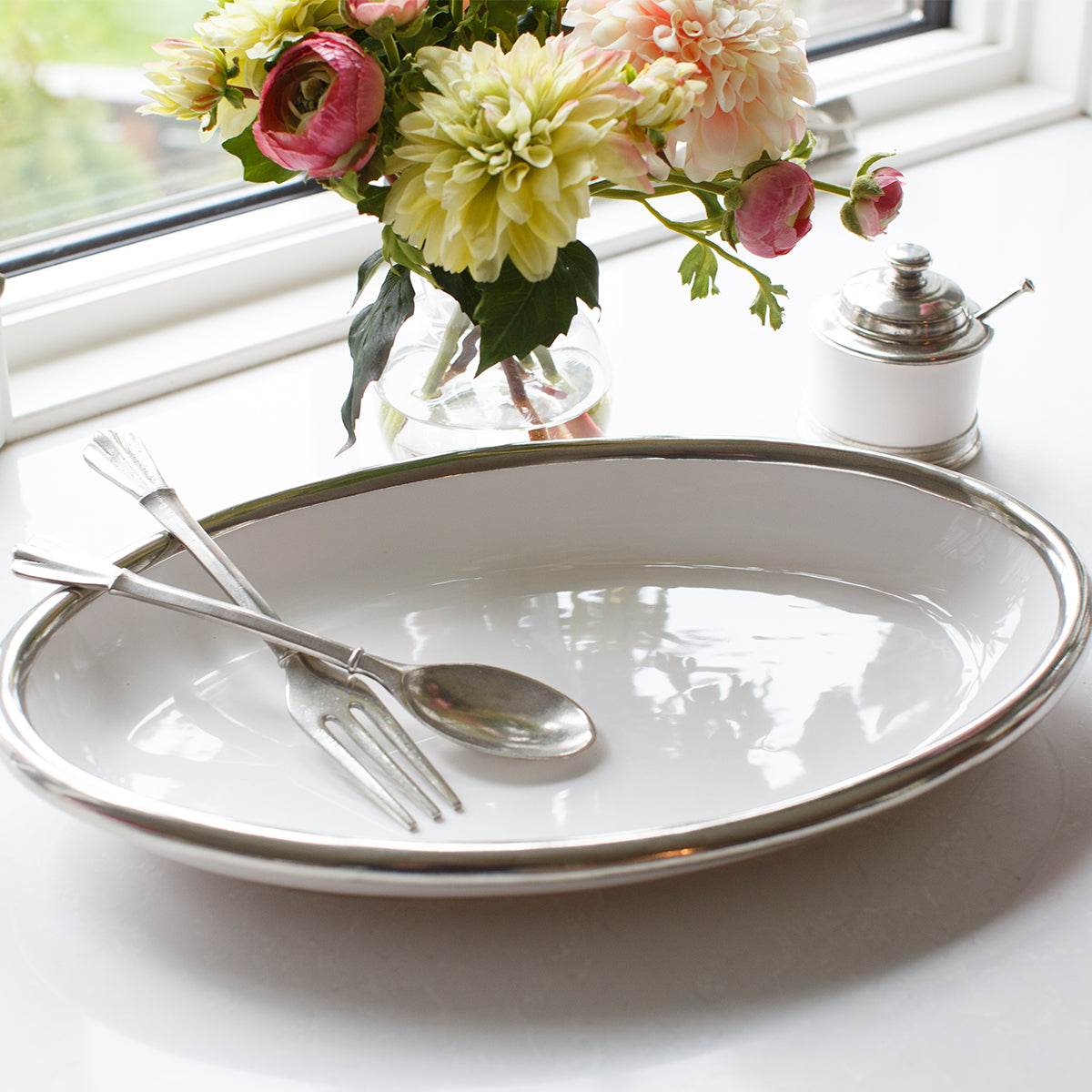 Tuscan White ceramic Oval Platter on a counter with flowers and a covered dish