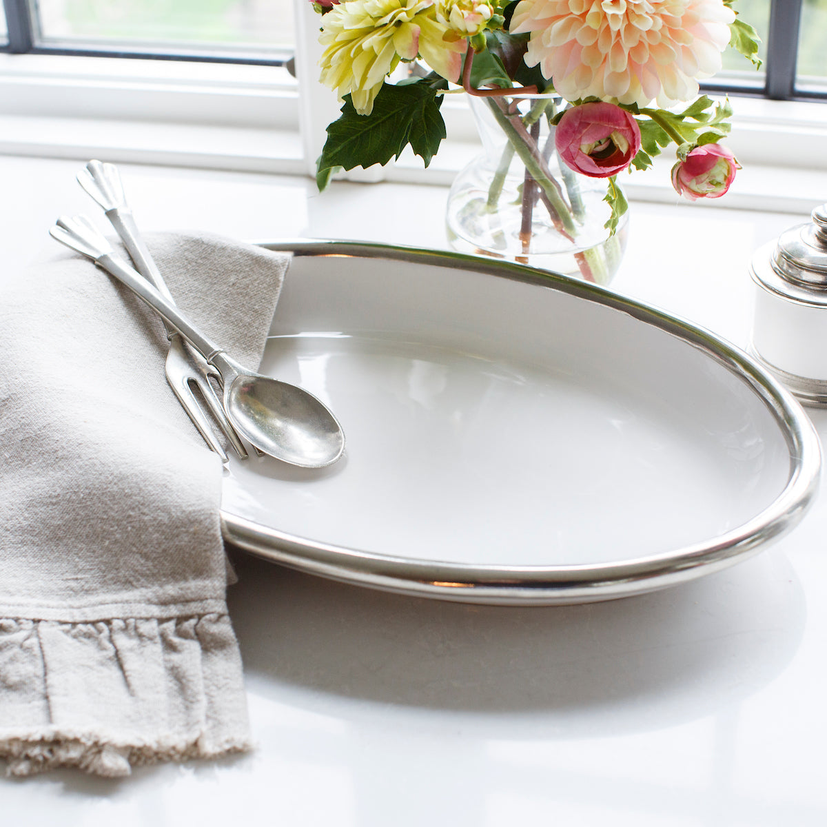 White Tuscan Oval Platter with Peltro Salad Servers and linen towel on counter