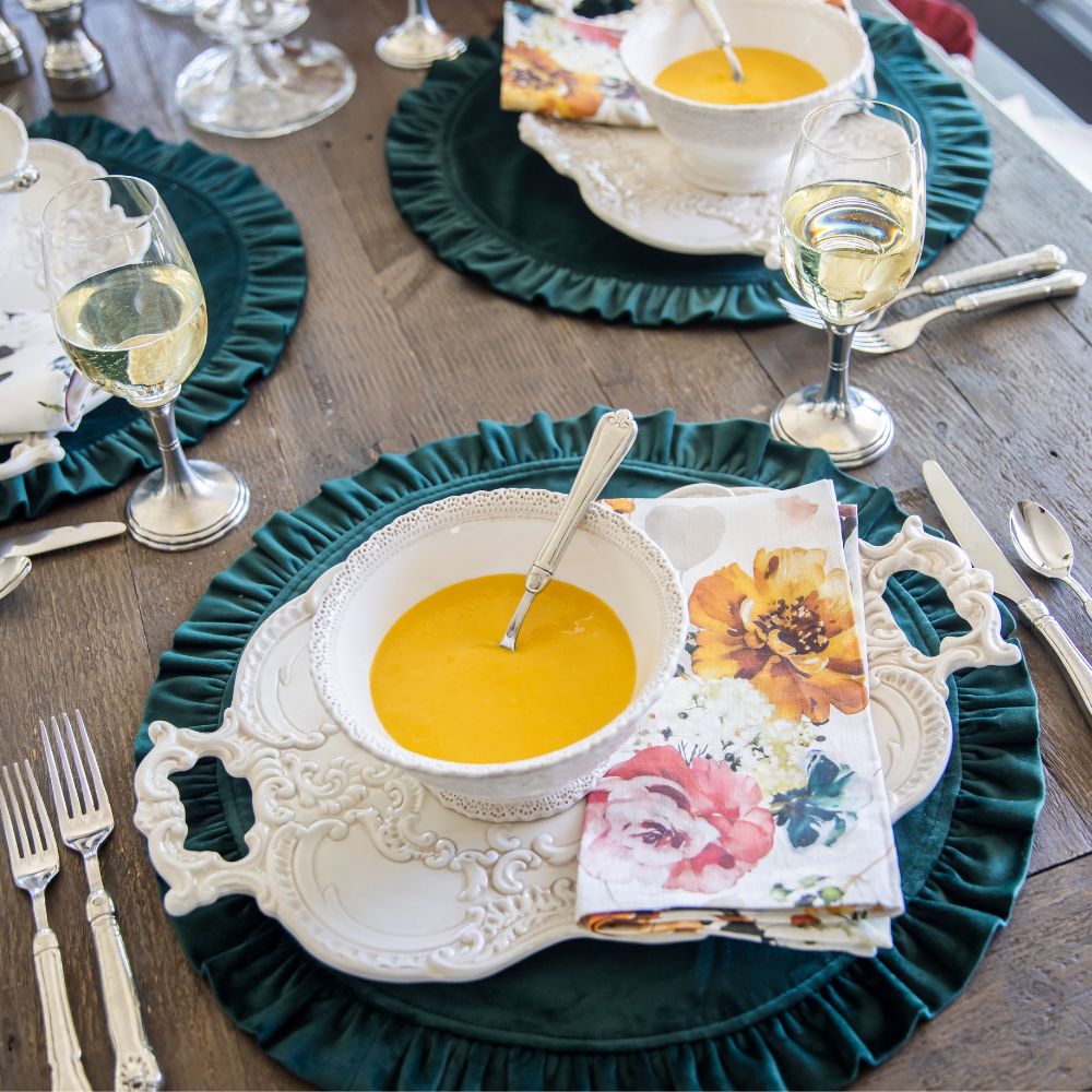 Dining table setting with green placemats, white bowls, and floral napkins.