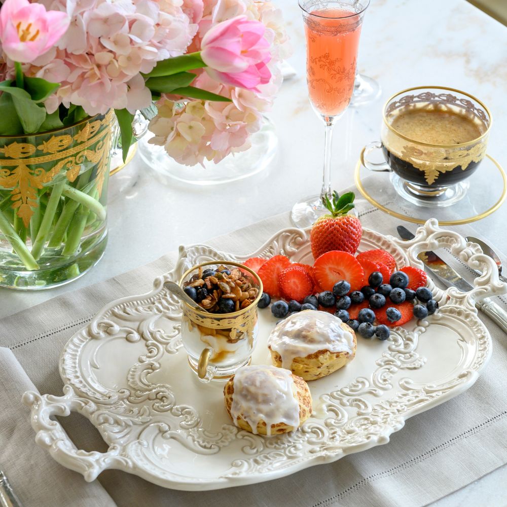 Decorative table setting with fruit, pastries, and flowers on a white tablecloth.