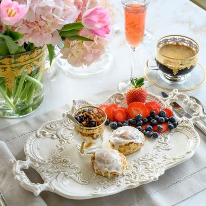 Decorative table setting with fruit, pastries, and flowers on a white tablecloth.