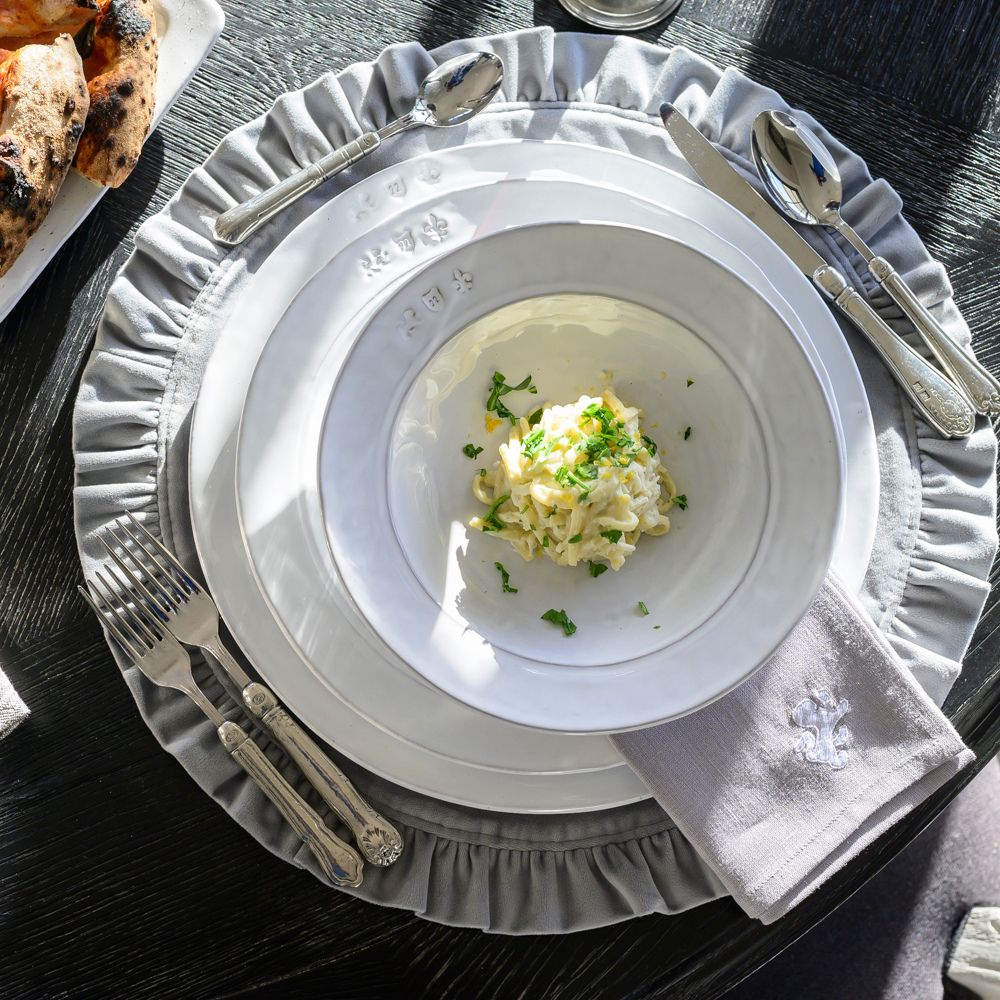 Firenze Pasta dish with a fettuccini on a white plate, surrounded by silverware and a gray napkin on a dark surface.