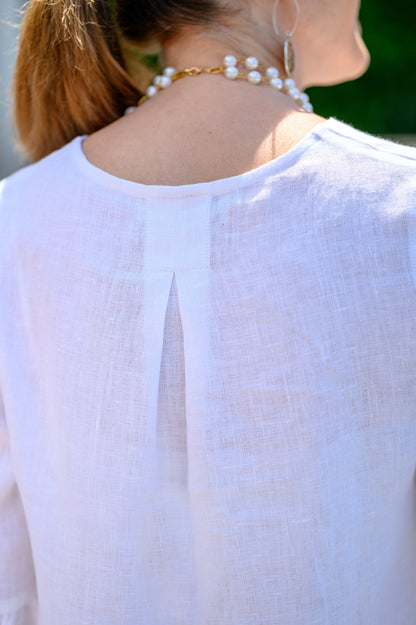 Back detail of top in white linen with model posing outside. --Arte Italica and Crown Linen Designs