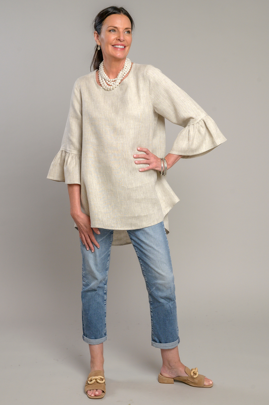Woman wearing a soft flax colored Bella linen top with 3/4 bell sleeves and jeans with a stacked pearl necklace and pewter bangles. --Arte Italica and Crown Linen Designs