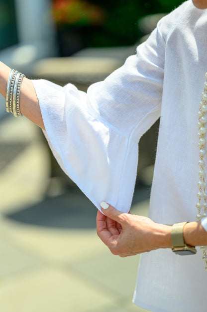Detailed shot of the ruffled bell sleeve in white linen with model posing outside. --Arte Italica and Crown Linen Designs