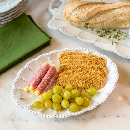 Plated Bella Bianca Beaded Platter with breaded meat, salami, and grapes on a marble surface.