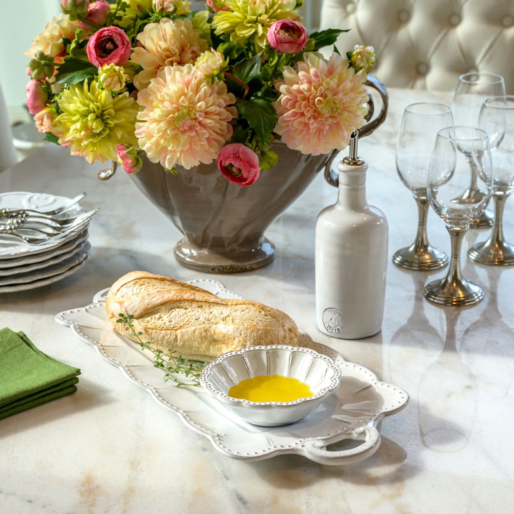 Table setting with bread and oil on a Bella Bianca Beaded Rectangular Tray and Oil Bottle on a marble surface with Flowers in background