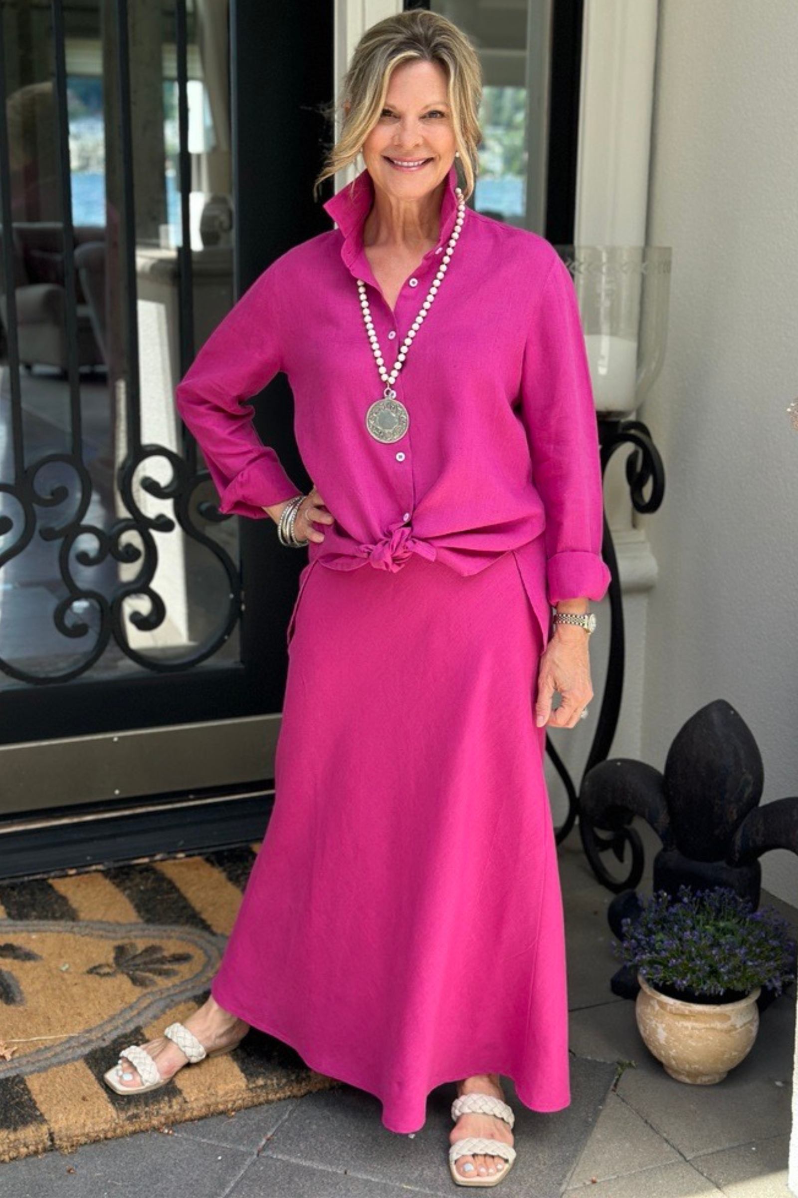 Woman posing wearing magenta linen top paired with beaded necklace and magenta Cindy skirt. --Arte Italica and Crown Linen Designs
