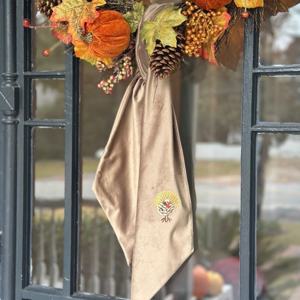 Mocha Velvet Sash Bow with Turkey embroidery hanging on a black metal door with autumn decorations.