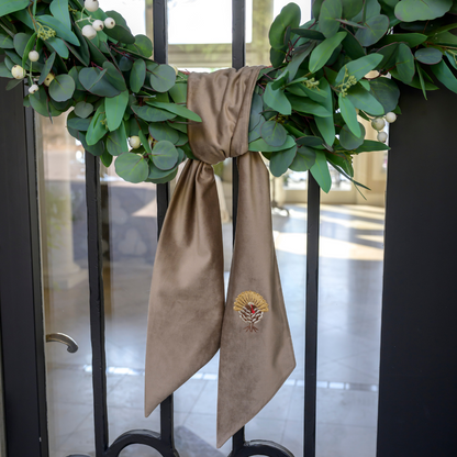 Green wreath with a Mocha Velvet Sash  featuring an embroidered turkey design on a glass door.
