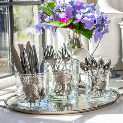 Arte Italica Damasco glass vessels in three sizes used as cutlery holders on a silver tray with purple hydrangeas