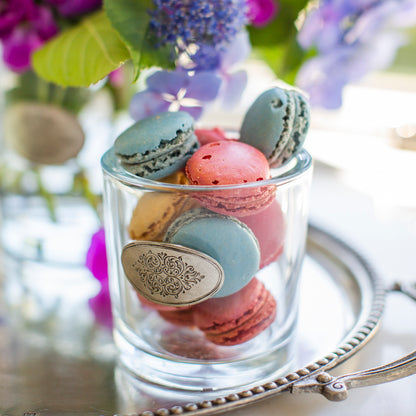 Arte Italica Damasco glass vessel filled with pastel French macarons on a silver tray with purple florals