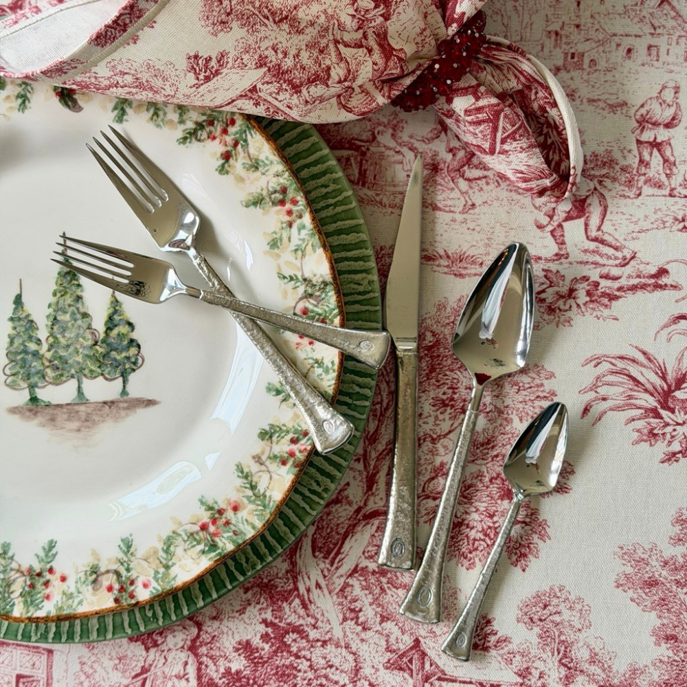 A five piece set of Elena flatware on a table with Red Montefalco toile tablecloth and Natale dinner plate