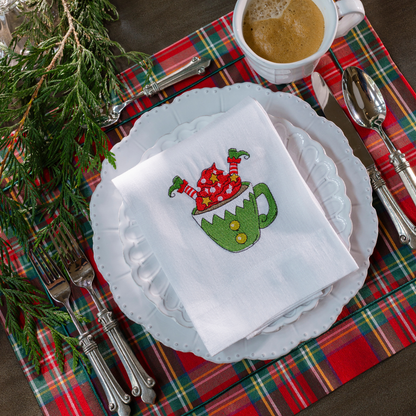 A Bella Bianca placesetting on a red tartan cotton placemat with an embroidered elf in a cup white linen towel folded on it