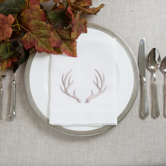 White Antler Linen Tri-Fold Napkin on gray tablecloth next to fall foliage 