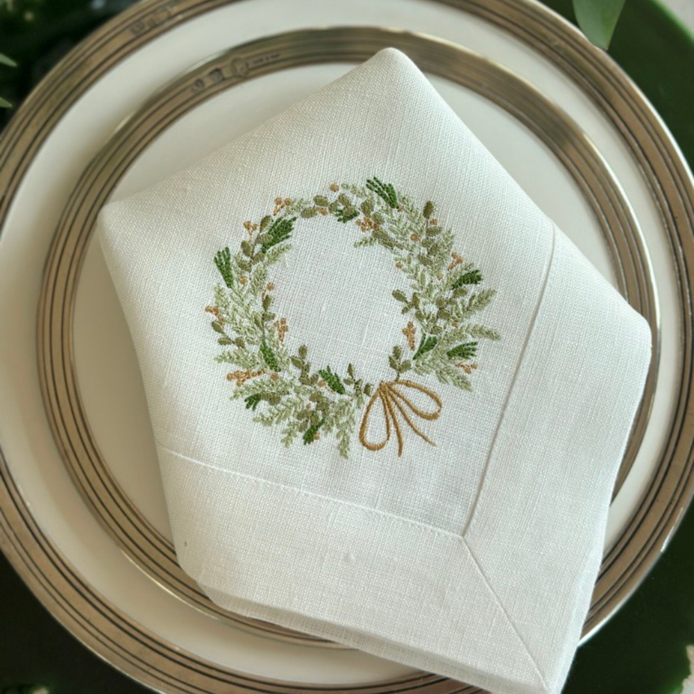 Napkin with embroidered wreath design on a plate