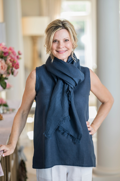 Woman wearing navy Farrah Fringe linen scarf wrapped at the neck over a matching navy linen top. --Arte Italica and Crown Linen Designs