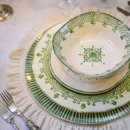 Stack of Green and white dishes on a cream velvet round placemat