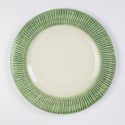 A round ceramic charger with a hand-painted striped pattern in green and cream colors.