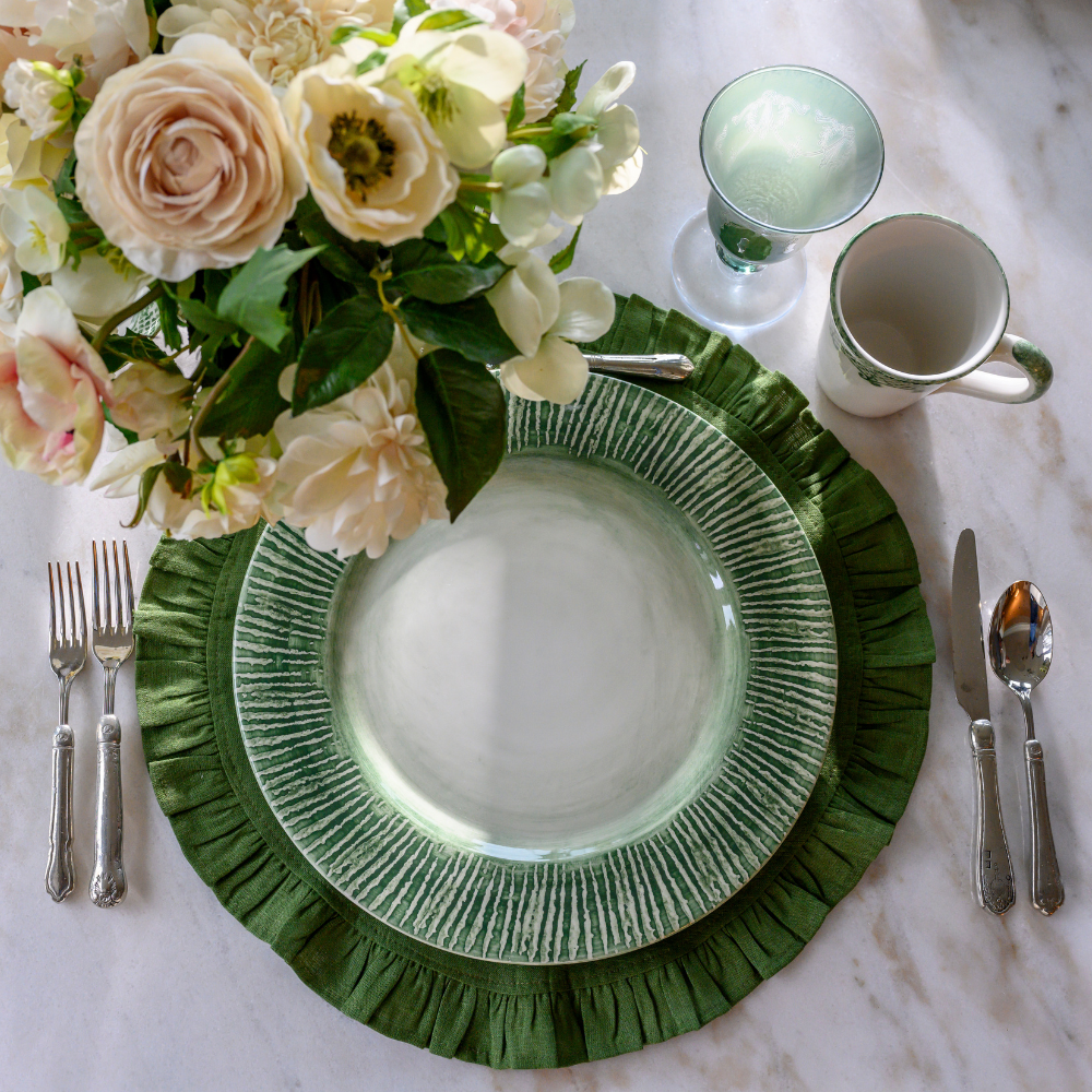 Green striped charger on an Evergreen Linen Placemat with flowers and flatware