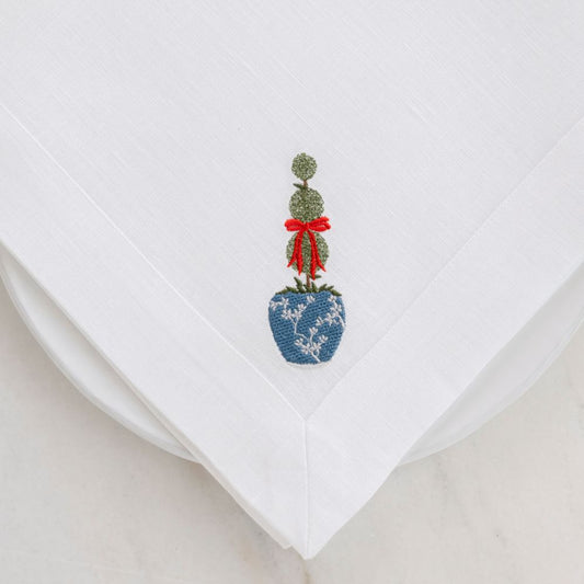 Embroidered La Jardin Triple Topiary White Linen Napkin with red bow on a White plate