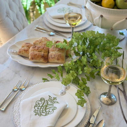 Table set with Leone dinnerware with green flowers and a platter with rolls and wine glasses on the table