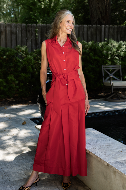A woman standing by a pool wearing a Lizzy taffeta skirt with a Caroline sleeveless top with a sash