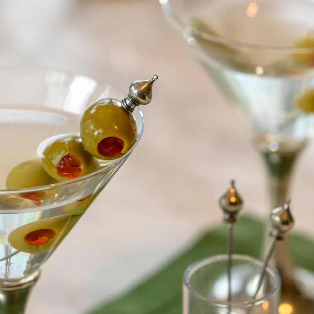 Close-up of a cocktail with olives on a Martini Crown pick with blurred background