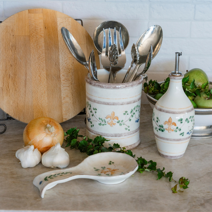 A counter set with a Medici ceramic spoon rest and oil bottle and utensil holder behind it